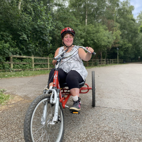 Lady in helmet on red adapted trike cycle